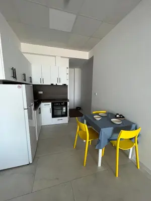a kitchen with a table and yellow chairs and a refrigerator at Aliara Dilara Beach Apartments in Pomorie