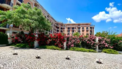 a building with red and pink flowers in a courtyard at Bratanov Cascadas Ravda in Ravda