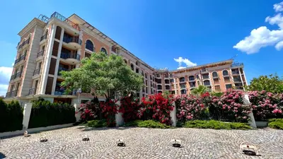 a building with a garden of flowers in front of it at Bratanov Cascadas Ravda in Ravda