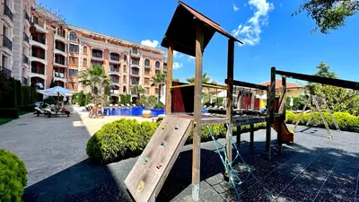 a playground with a wooden slide in a courtyard at Bratanov Cascadas Ravda in Ravda