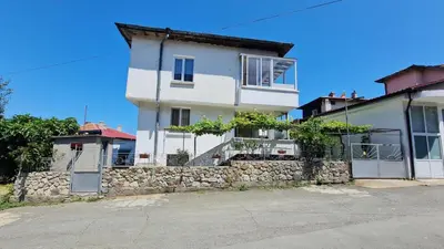 a white house with a stone wall at S Apartment in Tsarevo