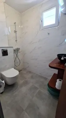 a bathroom with a toilet and a sink and a window at S Apartment in Tsarevo