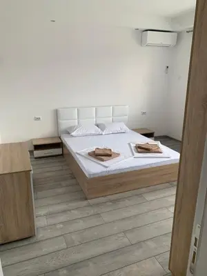 a bedroom with a white bed and a wooden floor at Апартамент Енигма/Apart Enigma in Sveti Vlas