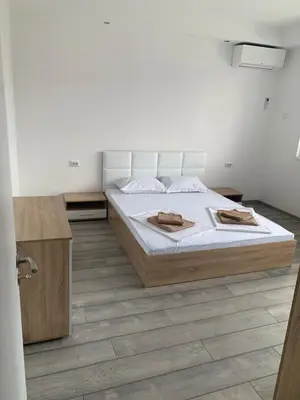a white bedroom with a bed and a wooden cabinet at Апартамент Енигма/Apart Enigma in Sveti Vlas