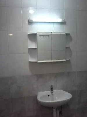 a white bathroom with a sink and a light at Morski Rai Apartments in Byala