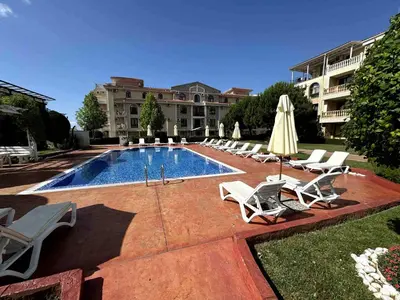 a pool with chairs and umbrellas next to a building at Apartment Royal Bay Sveti Vlas in Sveti Vlas