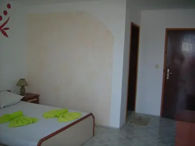 a bedroom with a bed with green pillows on it at Hotel Pasians in Pomorie