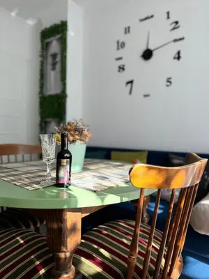 a table with a bottle of wine and a clock at The Master and Margarita Apartment, Майстора и Маргарита 2 in Burgas City