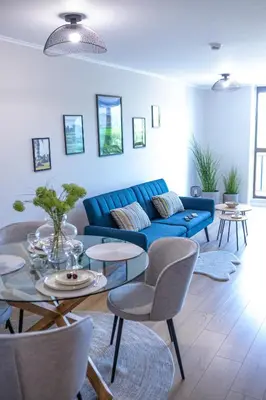 a living room with a blue couch and tables and chairs at Луксозен Апартамент в Модерна сграда -Молимаркс Делукс Апартамент Бургас in Burgas City