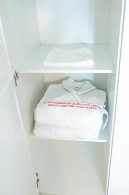 a closet with white shelves and a bed at Луксозен Апартамент в Модерна сграда -Молимаркс Делукс Апартамент Бургас in Burgas City