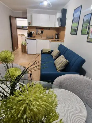 a living room with a blue couch and a table at Луксозен Апартамент в Модерна сграда -Молимаркс Делукс Апартамент Бургас in Burgas City