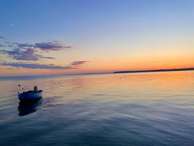 a small boat in the water at sunset at Budget First Sea Line Apt. FLORA in Pomorie