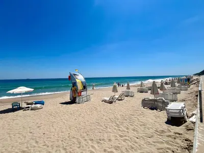 a beach with chairs and umbrellas and the ocean at Апартамент Бийч Вю Обзор - Apartment Beach View Obzor in Obzor