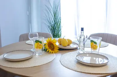 a wooden table with plates and glasses and oranges on it at Дизайнерско Студио в Модерна сграда -Молимаркс Делукс Студио Бургас in Burgas City