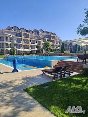 a swimming pool with benches and a large building at Apartments Atia Resort in Chernomorets
