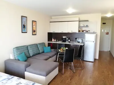 a living room with a couch and a kitchen at Apartments Atia Resort in Chernomorets