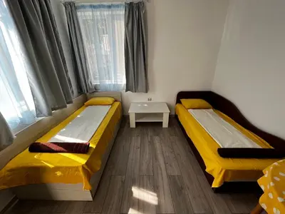 two beds in a small room with yellow sheets at Romance in Pomorie