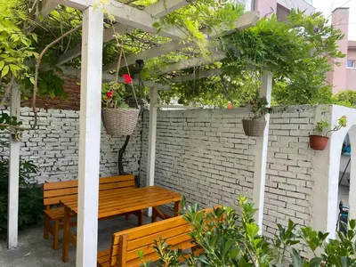 a wooden table and benches under a pergola with potted plants at Romance in Pomorie