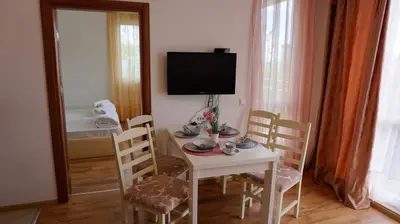 a room with a table with chairs and a television at Апартамент Атлантик Бяла - Apartment Atlantic Byala in Byala