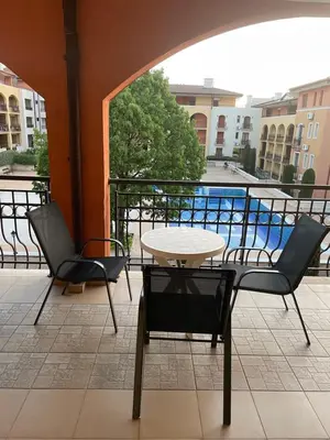a patio with a table and chairs and a pool at Galeria Holiday Apartments in Obzor