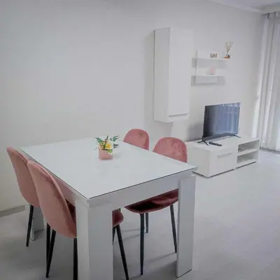a white dining room table with pink chairs and a tv at DiP HOME APARTMENTS in Pomorie