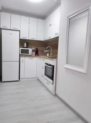 a white kitchen with white appliances and a window at DiP HOME APARTMENTS in Pomorie