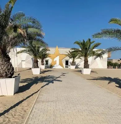 a walkway with palm trees and a building in the background at Apartament Esperanza in Sunny Beach