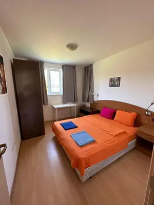 a bedroom with a bed with orange sheets and pink pillows at Sozopolis Hills - B1 - 3-room apart - 10 min from the beach in Sozopol
