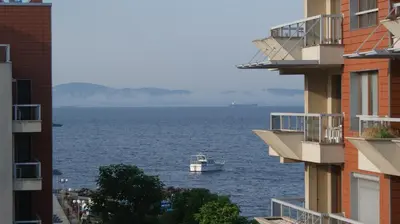 a boat in the water between two buildings at Cozy apartment with sea view and free parking in Pomorie