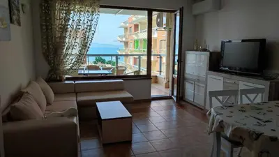 a living room with a couch and a large window at Cozy apartment with sea view and free parking in Pomorie