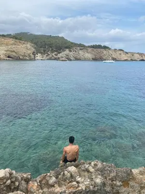 a man sitting on a rock in the water at Sunny Majestic Private Apartment in Sunny Beach