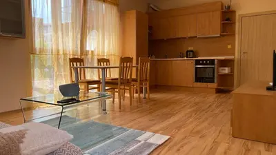 a living room with a glass table and a kitchen at Harmani Beach Apartment 4 in Sozopol