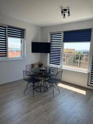 a dining room with a table and chairs and windows at Zagorovi -1 SP apartments in Burgas City
