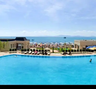 a large blue swimming pool with a view of the ocean at Studio Festa Pomorie in Pomorie