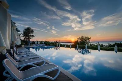 a swimming pool with lounge chairs and a sunset at 1 bedroom apartment in Santa Marina Sozopol in Sozopol
