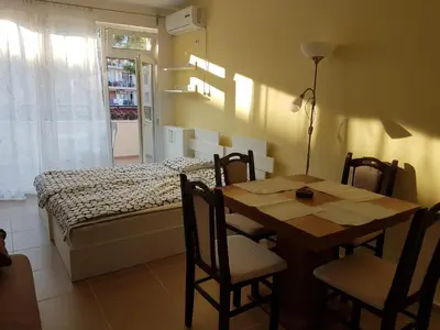 a dining room with a table and a bed at Apartament Iglika in Primorsko