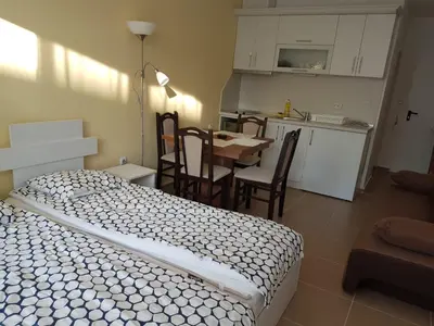 a bedroom with a bed and a table and a kitchen at Apartament Iglika in Primorsko