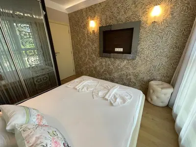 a bedroom with a white bed with a tv on the wall at Harmony Palace - Menada Apatments in Sunny Beach