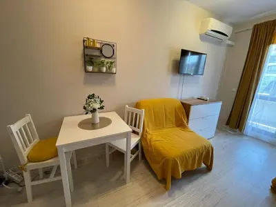 a living room with a table and a chair and a yellow blanket at U Dacha - Premium Apartments in Sunny Beach