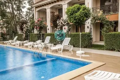 a hotel with a pool and chairs and a building at U Dacha - Premium Apartments in Sunny Beach