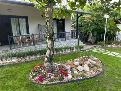 a tree in a garden with flowers and rocks at Villa Sea House 2 in Byala