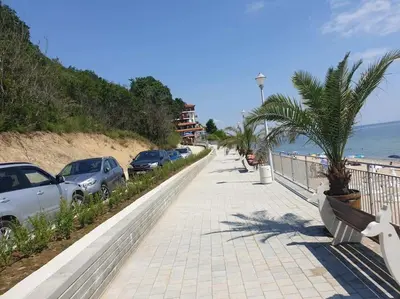 a sidewalk next to the beach with parked cars at Panoramic Sea View Apartment in Byala