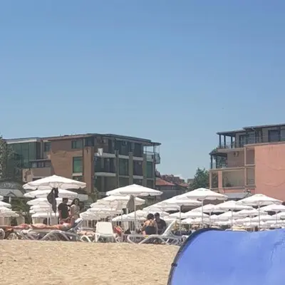 a group of white umbrellas and chairs on a beach at апартамент под наем на първа линия море in Sozopol