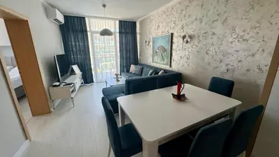 a living room with a table and blue chairs at Turtle Apartment Sunny Beach in Sunny Beach