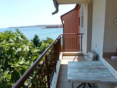 a balcony with a table and a view of the water at Farlalievi Guest House in Sozopol