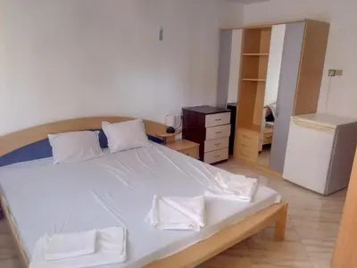 a bedroom with a bed with white sheets and a dresser at Farlalievi Guest House in Sozopol
