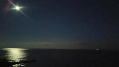 a full moon over the ocean at night at Coral Beach Apartment in Sveti Vlas