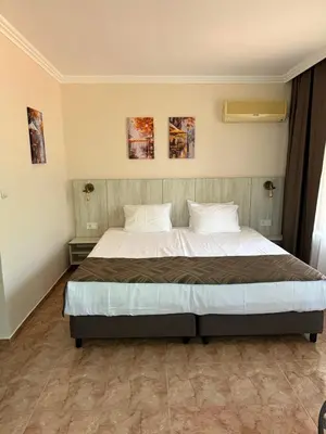 a bed in a bedroom with two paintings on the wall at Oleander House and Tennis Club in Sunny Beach