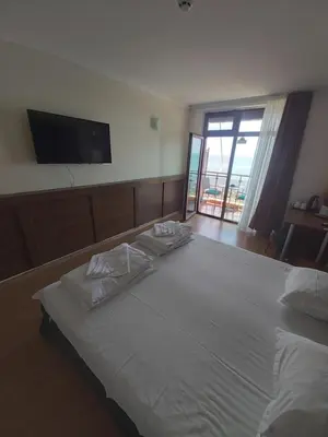 a bedroom with a large white bed with a flat screen tv at Guest Rooms Skalite in Sozopol