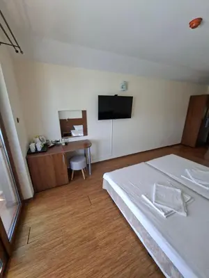 a bedroom with a bed and a desk with a television at Guest Rooms Skalite in Sozopol